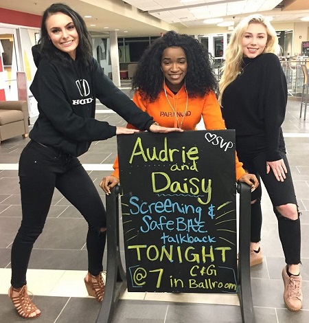 Daisy Coleman on the left  with her two friends showing the 'Audrie and Daisy' screening sign.